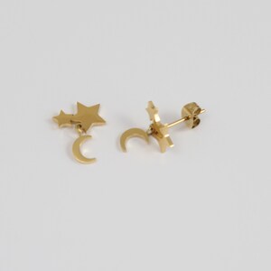 May include: Gold tone earrings with a crescent moon charm and two star charms dangling from the moon.