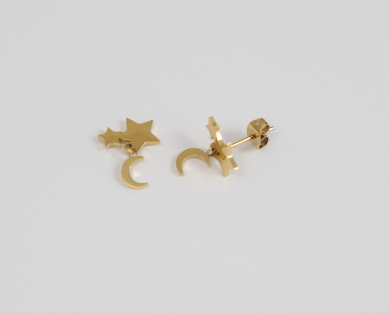 May include: Gold tone earrings with a crescent moon charm and two star charms dangling from the moon.