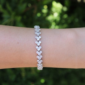 May include: A silver bracelet with a double row of clear cubic zirconia stones set in a heart shape.
