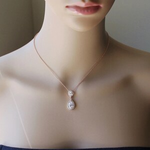 May include: A rose gold necklace with a teardrop-shaped pendant featuring two clear cubic zirconia stones.