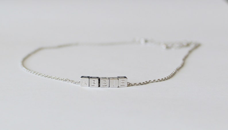 Puede incluir: Un brazalete de cadena de plata con el nombre "ABBIE" escrito en letras de bloque de plata.