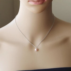 May include: A delicate silver chain necklace with a single pink pearl pendant.