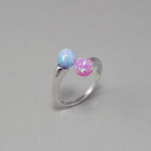 May include: A silver ring with two opal stones, one blue and one pink.