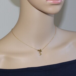 May include: A gold chain necklace with a crescent moon charm and three small star charms.