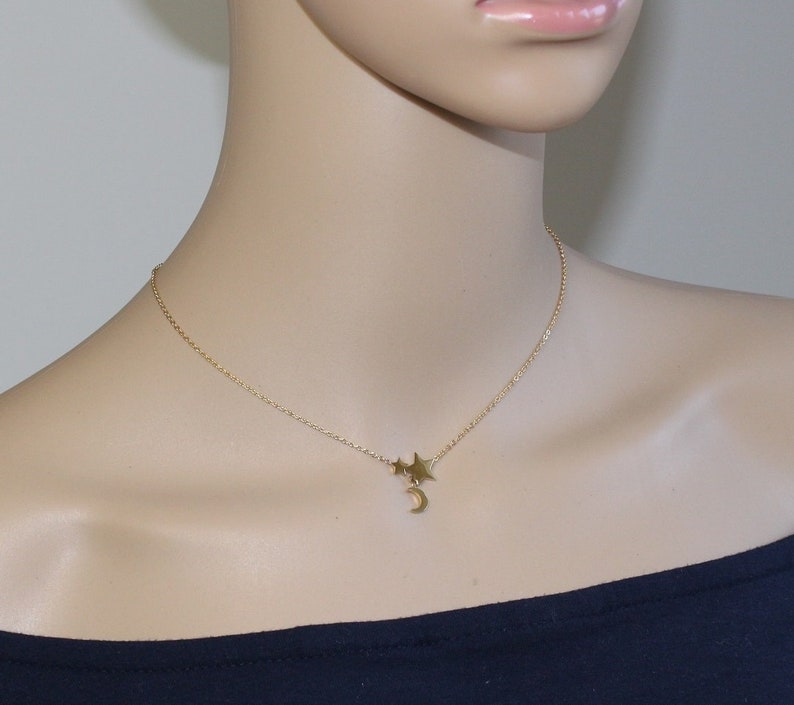 May include: A gold chain necklace with a crescent moon charm and three small star charms.
