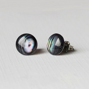 May include: A pair of silver stud earrings with iridescent black and blue round cabochon stones.