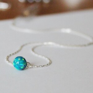 May include: A delicate silver chain necklace with a single round blue opal pendant.