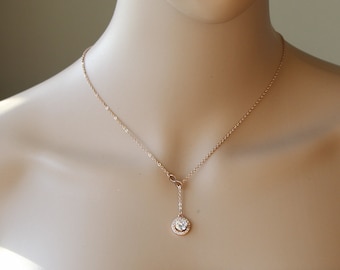 May include: A rose gold necklace with a small round pendant featuring a clear crystal surrounded by smaller crystals.