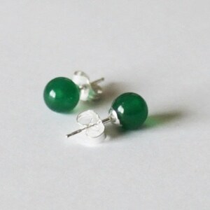 May include: A pair of green gemstone stud earrings with silver posts.