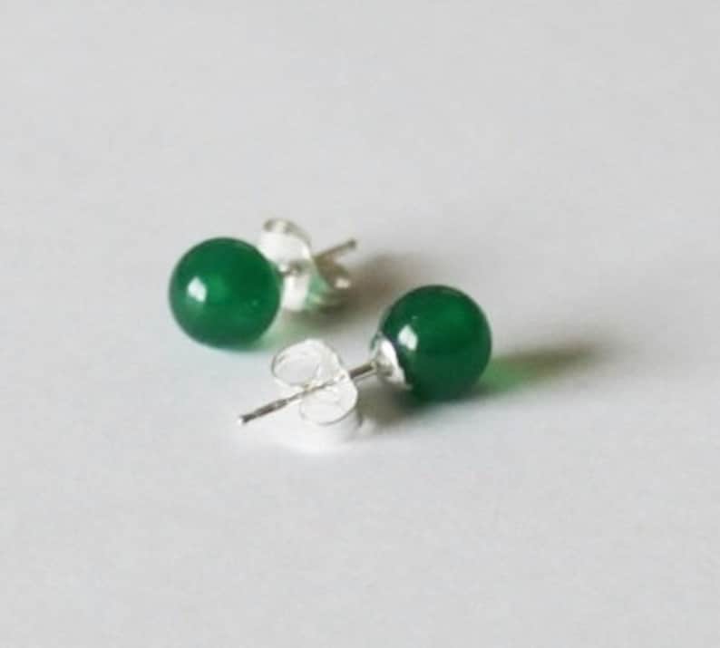May include: A pair of green gemstone stud earrings with silver posts.
