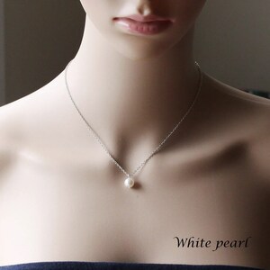 May include: A simple silver chain necklace with a single white pearl pendant. The necklace is on a mannequin's neck. "White pearl" is written in the bottom right corner of the image.