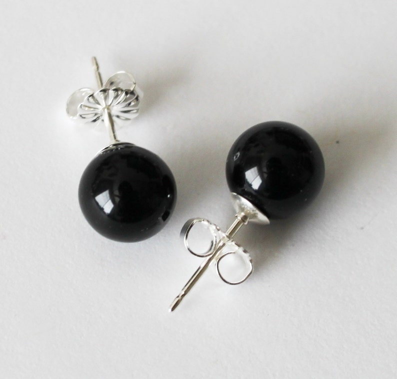 May include: A pair of black onyx stud earrings with silver posts and butterfly backs.