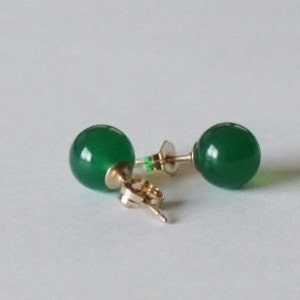 May include: A pair of green gemstone stud earrings with gold posts.