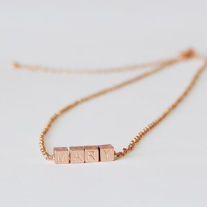 Puede incluir: Un collar de oro rosa con una cadena y un colgante que deletrea el nombre "MARY" en letras may&uacute;sculas.