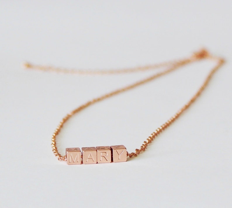 Puede incluir: Un collar de oro rosa con una cadena y un colgante que deletrea el nombre "MARY" en letras may&uacute;sculas.