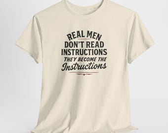 May include: Cream-colored t-shirt with the text "REAL MEN DON'T READ INSTRUCTIONS THEY BECOME THE INSTRUCTIONS" in black and red lettering. The shirt has short sleeves and a crew neck.