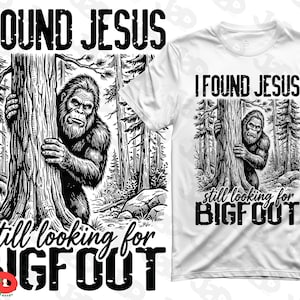 May include: White t-shirt with a black and white graphic of Bigfoot peeking from behind a tree in a forest. Text above the graphic reads "I FOUND JESUS" and below it reads "still looking for BIGFOOT."