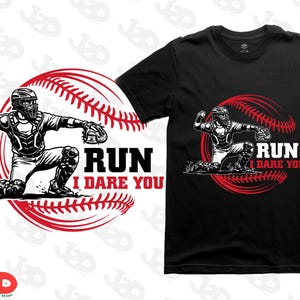 Op de afbeelding: Zwart T-shirt met een honkbalvanger-afbeelding in zwart en wit, tegen een rood honkbalontwerp. De tekst "RUN I DARE YOU" staat in vette, witte letters.