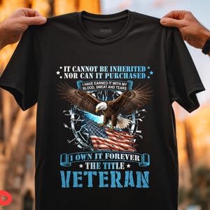 May include: Black t-shirt featuring a majestic bald eagle with outstretched wings, perched above an American flag. The shirt includes the text "IT CANNOT BE INHERITED NOR CAN IT PURCHASED" and "VETERAN".