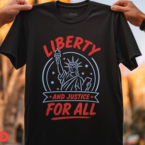May include: A black short-sleeved t-shirt featuring a graphic of the Statue of Liberty in light blue lines. The text LIBERTY in red arches above, with AND JUSTICE FOR ALL in red below, all enclosed within a circular frame with small stars.