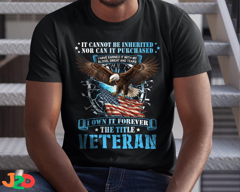 May include: Black t-shirt with a graphic featuring an eagle with outstretched wings above an American flag. Text includes "IT CANNOT BE INHERITED NOR CAN IT PURCHASED" and "I OWN IT FOREVER THE TITLE VETERAN."