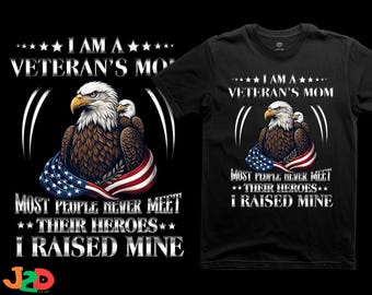 May include: A black t-shirt featuring a graphic of two bald eagles draped in an American flag. The text reads: I AM A VETERAN'S MOM, MOST PEOPLE NEVER MEET THEIR HEROES, I RAISED MINE. The design includes white stars and distressed lettering.