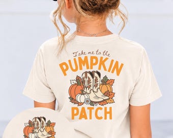May include: A cream-colored t-shirt featuring a graphic on the back with the text Take me to the PUMPKIN PATCH. The design includes orange pumpkins, autumn leaves, and a pair of cowboy boots. A smaller version of the graphic is shown below.