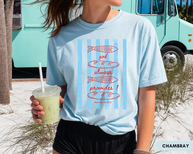 Woman wearing oversized Comfort Colors Christians shirt featuring God Always Provides graphic with fish illustrations and Matthew 14:13-21 Bible verse in vintage aesthetic style.