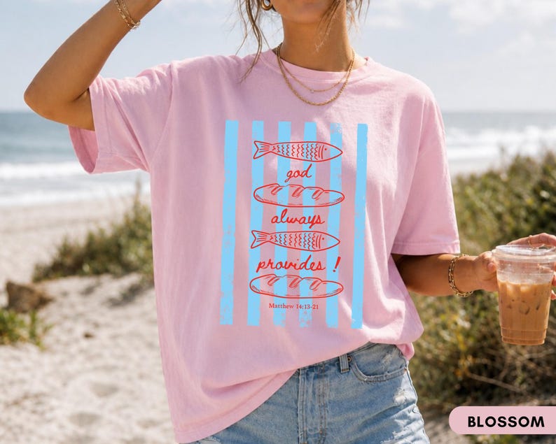 Woman wearing oversized Comfort Colors Christians shirt featuring God Always Provides graphic with fish illustrations and Matthew 14:13-21 Bible verse in vintage aesthetic style.