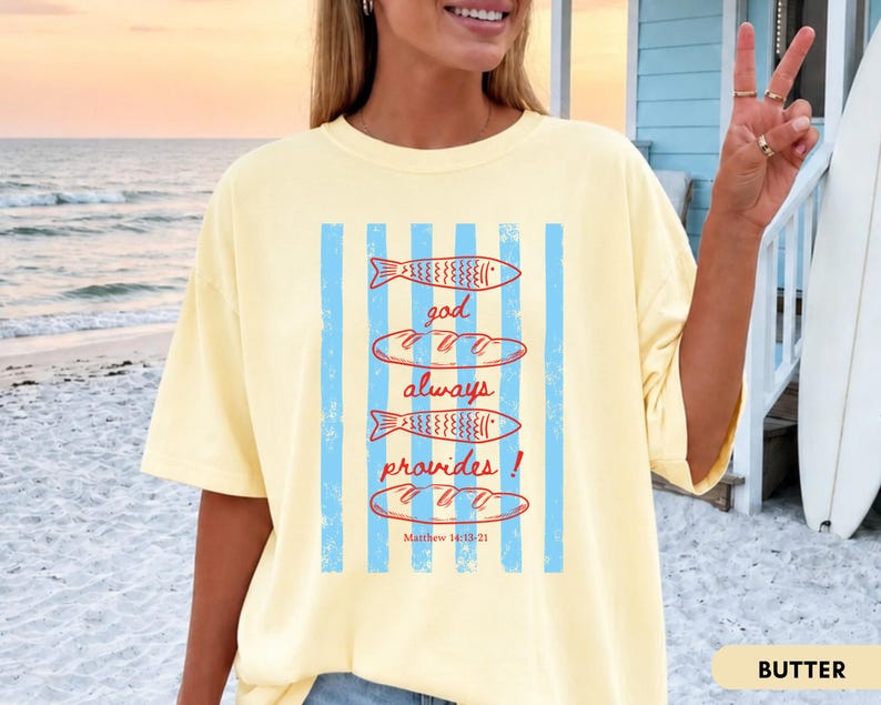 Woman wearing oversized Comfort Colors Christians shirt featuring God Always Provides graphic with fish illustrations and Matthew 14:13-21 Bible verse in vintage aesthetic style.