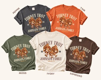 May include: Five short-sleeve crew neck t-shirts in pepper, yam, moss, ivory, and espresso colors. Each shirt features a graphic of three turkeys running with the text Turkey Trot, 2026, Johnson Family, and Dallas, TX printed on the front.