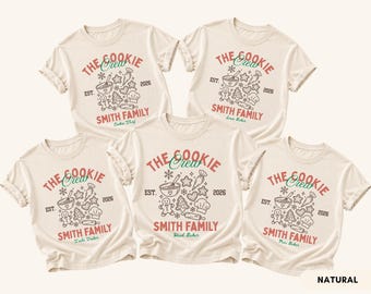 May include: Five cream-colored short-sleeve t-shirts featuring a graphic print with the text THE COOKIE CREW, SMITH FAMILY, EST. 2026, and various baking illustrations including a gingerbread man, whisk, rolling pin, and chef hat.