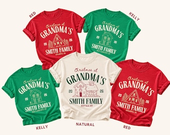 May include: Five short-sleeved t-shirts in red, kelly green, and natural colors. Each shirt features a graphic with the text "Christmas at GRANDMA'S", "SMITH FAMILY", the year "20 26", and a line-art illustration of a house or cabin with a location.
