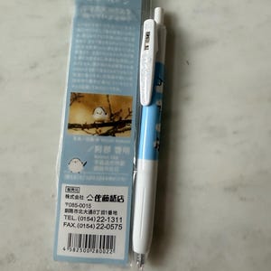May include: A white and light blue ballpoint pen with a bird illustration and Japanese text. The pen is packaged with a blue card featuring a bird illustration and Japanese text. The packaging includes the text "シマエナガさん" and "阿部啓明".