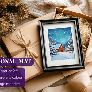 May include: A framed winter landscape painting with a red cabin, snow-covered trees, and a starry sky. The painting is in a black frame, resting on a gift box with a beige ribbon. The words "OPTIONAL MAT" are visible.