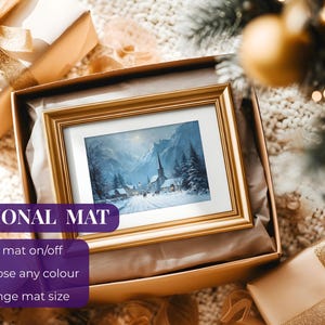 May include: A framed winter landscape painting with a gold frame, presented in a gift box. The painting depicts a snow-covered village with a church and mountains in the background. The box is surrounded by wrapped gifts.