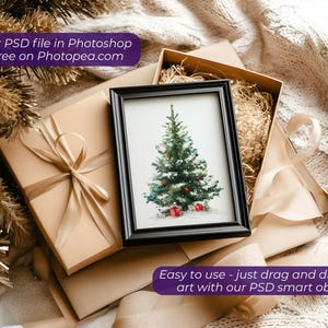 May include: A framed watercolor print of a Christmas tree with red gift boxes, set inside a gift box with decorative ribbon. The image is surrounded by gift boxes and festive decorations. Text on the image reads: Use your PSD file in Photoshop or for free on Photopea.com and Easy to use - just drag and drop your art with our PSD smart objects.