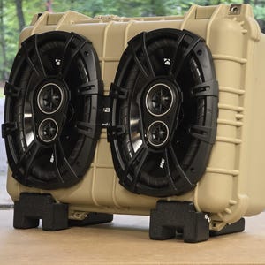 Peut inclure: Enceinte acoustique beige avec deux grands haut-parleurs noirs. Les haut-parleurs ont une conception à double cône et sont montés à l'avant du boîtier. Le boîtier repose sur des pieds en mousse noirs.