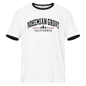 May include: A white ringer t-shirt with black trim on the collar and sleeves. The chest features black text reading BOHEMIAN GROVE in an arched font, a horizontal red line with three small pine tree icons and two stars, and CALIFORNIA below.