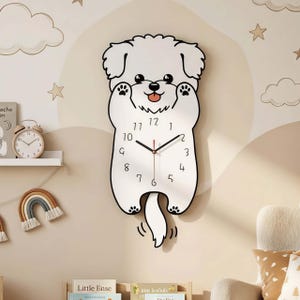 Puede incluir: Un reloj de pared blanco con forma de perro, con contornos negros y un segundero rojo. El reloj presenta un diseño lúdico con patas y una cola que se mueve. La esfera muestra números y agujas negras.