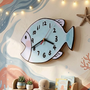 May include: A light blue fish-shaped wall clock with black numerals and hands. The clock has a wooden frame and is mounted on a wall with a sea-themed mural. The clock's dimensions are not visible.