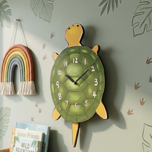 May include: A novelty turtle-shaped wall clock with a green shell and yellow details. The clock face has white numerals and black hands. A rainbow wall hanging and children's books are also visible.