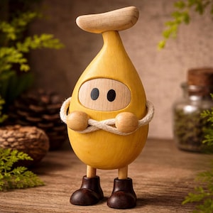 Pode incluir: Uma figura de madeira caprichosa em forma de gota amarela com cabeça e pés de madeira. A figura tem olhos pretos e usa botas marrons. Uma corda é enrolada ao redor do corpo, sobre uma superfície de madeira.