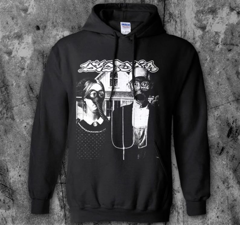 Puede incluir: Sudadera con capucha negra con estampado gr&aacute;fico. El estampado presenta una pareja con m&aacute;scaras de gas frente a una casa, con la palabra "Avaritia" encima en una fuente estilizada. El dise&ntilde;o es en blanco y negro.