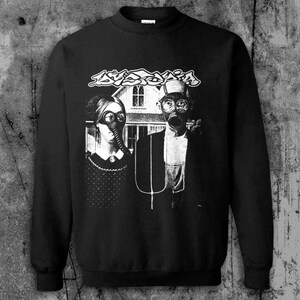 Puede incluir: Sudadera negra con un gr&aacute;fico en blanco y negro de una pareja con m&aacute;scaras de gas frente a una casa. La palabra "AVOID" est&aacute; impresa encima de la pareja en una fuente estilizada.