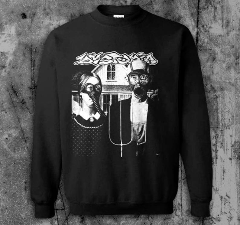 Puede incluir: Sudadera negra con un gr&aacute;fico en blanco y negro de una pareja con m&aacute;scaras de gas frente a una casa. La palabra "AVOID" est&aacute; impresa encima de la pareja en una fuente estilizada.