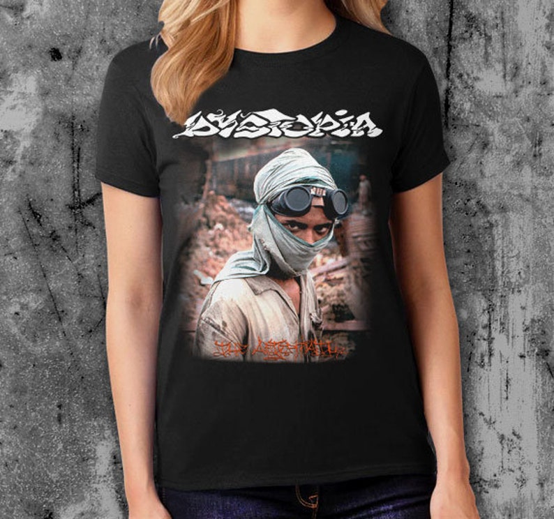 K&ouml;nnte beinhalten: Schwarzes T-Shirt mit einem Grafikdruck einer Person, die ein gr&uuml;nes Bandana und eine Schutzbrille tr&auml;gt. Der Text "Dystopia" ist in Wei&szlig; &uuml;ber dem Grafikdruck gedruckt. Der Text "The Last Man" ist in Rot unter dem Grafikdruck gedruckt.