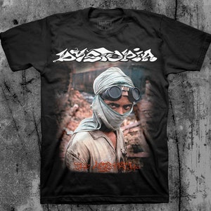 K&ouml;nnte beinhalten: Schwarzes T-Shirt mit einem wei&szlig;en Aufdruck einer Band namens "Dyspepsia". Der Aufdruck zeigt eine Person mit einem Gesichtsschutz und einer Schutzbrille, darunter der Text "The Agitator".