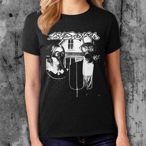 Puede incluir: Camiseta negra con un gr&aacute;fico en blanco y negro de una pareja con m&aacute;scaras de gas, una casa y la palabra "Dyslexia". El dise&ntilde;o es una parodia de la pintura American Gothic.
