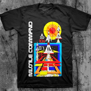 May include: Black t-shirt with a retro video game design featuring a spaceship, a target, and the text "Missile Command" and "ATARI 109".